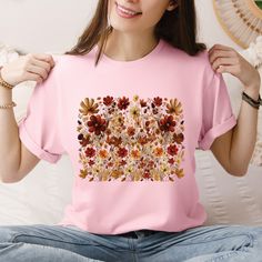 Step into a world of nature-inspired style with our Boho Cottagecore T-shirt, featuring a stunning design of vintage pressed wildflowers. Crafted from 100% soft, breathable cotton, this floral crewneck tee offers comfort and versatility, making it perfect for layering or wearing alone. The natural fibers ensure that you stay cozy while showcasing your love for all things botanical, making it an essential addition to any wardrobe vintage pressed flowers shirt is not only a fashionable choice but Nature-inspired Tops With Plant Print For Summer, Pink Crew Neck Top With Plant Print, Summer Nature-inspired Tops With Plant Print, Botanical Style Flower Graphic Print Tops, Botanical Crew Neck Top With Graphic Print, Spring Nature-inspired Tops With Graphic Print, Nature-inspired Crew Neck T-shirt For Summer, Nature-inspired Summer Tops With Plant Print, Summer Nature-inspired Crew Neck T-shirt