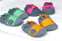 four pairs of baby shoes are shown on a white sheet with pink, green and yellow accents