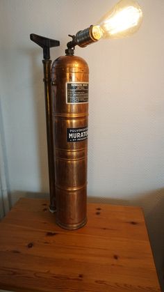 an old fashioned fire extinguisher on a wooden table with a light bulb