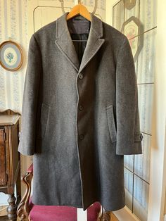 This simple overcoat from Panda by Whitehall is made from a wool blend in charcoal grey. It has the original buttons, two front pockets and two inside pockets, and it's fully lined with black silky lining. The measurements, taken with the coat lying flat, are: shoulder to shoulder,  18 inches; armpit to armpit, 22 inches; sleeves, 25 inches; length, 42 inches; bottom edge, 32 inches. Please note that there is some discolouration around the collar and a repair has been made in the back - see phot Classic Gray Wool Coat For Business, Classic Gray Pea Coat With Buttons, Classic Gray Pea Coat For Business, Classic Gray Wool Coat For Winter, Gray Wool Pea Coat For Business, Classic Gray Wool Coat With Pockets, Gray Business Wool Coat With Pockets, Gray Wool Coat With Pockets For Business, Business Gray Wool Coat With Pockets