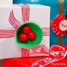 two red cherries in a paper bowl on top of a present box