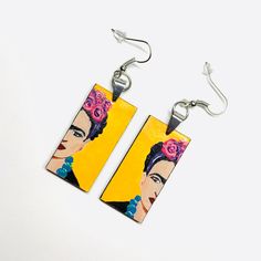 These Frida-inspired earrings are a true work of art, with each element carefully assembled by hand. Made with high quality acrylic paint and protected with a glossy finish, they are not only beautiful but also durable. With their light weight and one-of-a-kind design, they make the perfect gift for someone special. A truly unique accessory for a truly unique person. Size: 3/4 Inch x 1.5 Inch each (without including earrings hook wires).______________________________________ • GET IT FAST!Get it fast! Ready to ship on 1 to 3 business days* • ORDER NOW!Limited Quantities / Limited Edition. • FREE GIFT BOX INCLUDED!Fridamaniacs delivers every jewelry or gift order in a gift box. Thank you for shopping with us!____________________________ * Colors/Designs might slightly vary from actual. Our Artisan Yellow Earrings As Gift, Artisan Yellow Earrings For Gift, Artistic Hand Painted Earrings For Gifts, Artistic Resin Earrings For Pierced Ears, Yellow Earrings With Artistic Design For Gift, Artistic Resin Earrings With Ear Wire, Yellow Hand Painted Artsy Earrings, Hand Painted Yellow Artsy Earrings, Artsy Yellow Earrings With Artistic Design