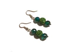 Prepare to elevate your style with these enchanting green dangle earrings that are destined to steal the spotlight. Imagine pairing them with your favorite outfit and watch as heads turn in awe. Crafted with meticulous detail, these one-of-a-kind earrings feature mesmerizing green lampwork and emerald green beads, suspended gracefully from sterling silver French ear wire hooks. Picture yourself donning these statement earrings, each pair measuring a chic 2 ½ inches in length. Unleash your inner Green Crystal Drop Earrings With Dangling Beads, Elegant Green Beaded Drop Earrings, Green Emerald Drop Crystal Earrings, Green Emerald Drop Earrings, Nickel-free Green Beaded Earrings For Parties, Handmade Green Crystal Drop Earrings, Elegant Green Beaded Crystal Earrings, Green Beaded Earrings With Round Beads, Green Jewelry With Dangling Round Beads