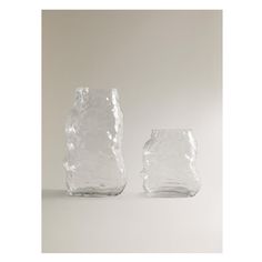 two clear vases sitting side by side on a white surface with no one in the photo