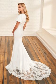 a woman in a white wedding dress standing on a wooden floor with her back to the camera