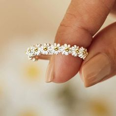 a woman's hand holding a ring with daisies on it