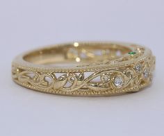 an intricately designed wedding band is shown in yellow gold, with diamonds on each side