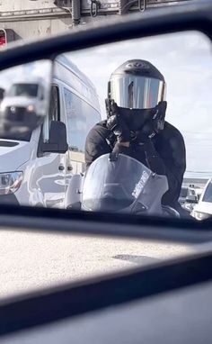 the reflection of a man in a side view mirror wearing a helmet and holding a camera