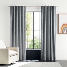 a white chair sitting in front of a window with curtains hanging on the windowsill