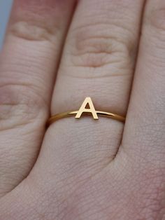 This elegant gold initial ring is perfect for stacking, making it a great gift for any occasion - whether a mother's day surprise or a best friend's birthday present. Crafted from quality stainless steel, this letter ring will look beautiful for years to come. Featuring a letter of your choosing, this ring can be worn alone or stacked making it perfect for gifting to friends or family. The subtle, yet sweet letter ring looks elegant alone or as part of a larger stack. This gold letter ring is th Everyday Gold Stackable Rings With Initials, Gold Stackable Rings With Initials For Everyday, Dainty Gold Stackable Rings With Initials, Simple Anniversary Rings With Initials, Simple Anniversary Ring With Initials, Simple Gold Stackable Initial Ring, Simple Gold Initial Ring For Anniversary, Everyday Gold Monogram Initial Ring, Gold Monogram Initial Ring For Everyday