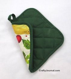 a green oven mitt with an apple print on the front and bottom, hanging from a white background