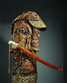 an elaborately decorated coat with a long wooden stick in it's left hand