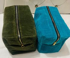 two green and blue bags sitting next to each other on top of a white bed