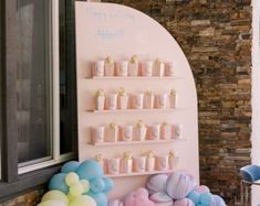 a pink and blue dessert bar with balloons on the wall next to it's display