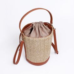 Made from high quality Raffia. Vegan leather trim. Polyester lining. Our raffia line are all made with an interior liner to keep your items safe and enclosed from beach sand or any harsh environment. Great size for traveling and for the summer heat.  Detachable shoulder strap included. Dimensions: 150x215X150mm Weight:  286g (bag) SHIPPING:  Free shipping from South Korea, estimated 7-14 days to get to you from purchase date.  RETURNS:  Return address is in USA so that returns can be made and given fast.  Returns up to 2 weeks starting when the shipping is completed.  Returns must be with tags.  Buyer must pay for return shipping unless item was damaged or incorrect.  Money will be refunded after we receive and inspect the item. Orders over $250 will have to pay 20% restocking fee. Brown Bucket Bag With Braided Handles For Beach Season, Brown Woven Bucket Bag For Day Out, Brown Bucket Bag With Adjustable Strap For Vacation, Natural Jute Bucket Bag With Braided Handles, Woven Natural Fiber Basket Bucket Bag, Straw Bucket Bag For Travel, Brown Bucket Crochet Bag For Beach Season, Brown Bucket Shoulder Bag For Beach, Straw Travel Bucket Bag