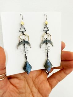 These cosmic sign earrings are rich with cosmic symbols - earth element, solar eclipse, and crescent moon - that together help with emotional balance and to protect against negative energies.  The diamond shaped labradorite is an additional layer of protection. It fills our aura with positivity, giving us the emotional strength and will to go through difficult spiritual transformations. I oxidize and hand finish some of the sterling silver elements to bring out contrast, and achieve an ombre eff Cosmic Symbols, Moon Earth, Earth Element, Emotional Strength, Spiritual Transformation, Earth Elements, Art Pendant, Ombre Effect, Emotional Balance