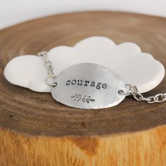 It only takes one little word to touch someone’s heart.This inspirational word bracelet makes a memorable gift idea that your recipient is sure to cherish. Artistically designed to perfection, it features a large oval shaped pendant stamped with the word “courage” and a whimsical leaf motif. Suspended from coordinating chain, it features a delicately hand hammered edge that adds layers of character. When worn, it caresses the top of your wrist beautifully and is sure to become a treasured access Meaningful Adjustable Charm Bracelet, Inspirational Nickel-free Bracelets As Gift, Inspirational Nickel-free Bracelets For Gifts, Inspirational Nickel Free Bracelets As Gift, Inspirational Nickel-free Bracelets As A Gift, Inspirational Sterling Silver Nickel-free Bracelets, Inspirational Engraved Bracelets For Everyday, Inspirational Engraved Everyday Bracelets, Inspirational Sterling Silver Friendship Bracelets