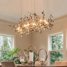 a chandelier hanging from the ceiling in a dining room with chairs around it