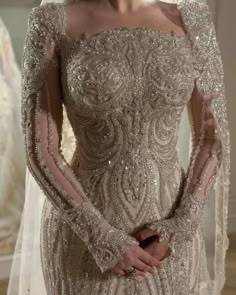 a woman in a wedding dress with long sleeves and beading on her shoulders, wearing a