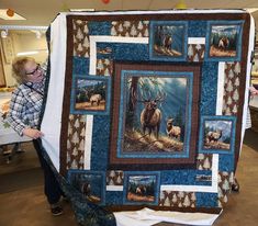 a woman holding up a quilt with pictures of animals on it