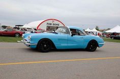 a blue car parked in front of a white tent