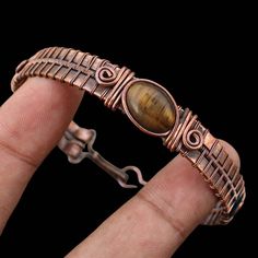 Tigers Eye Bracelet Copper Wire Wrapped Cuff Bracelet Copper Bangle Tigers Eye Cuff Bangle Handmade Bracelet Wire Wrapped Bangle Jewelry Main Stone - Tigers Eye Bangle Length - 2.50 - 2.75" Inches (Adjustable) Bangle Width  -  0.50 Inches Metal                  -  Copper Copper Has Been Used For Jewelry Making For Thousands Of Years, Dating Back To Ancient Civilizations Such As The Egyptians, Romans, And Aztecs. Copper Was Valued For Its Beauty, Versatility, And Durability, And Was Often Used To Handmade Metal Bracelet In Brown, Silver Cuff Bracelets Made Of Copper, Handmade Metal Wrap Bracelet In Bangle Shape, Unique Adjustable Cuff Bracelet, Handmade Brown Metal Bracelet, Handmade Adjustable Metal Bracelets, Adjustable Metal Bangle With Bracelet Strap, Handmade Adjustable Copper Bracelet, Handmade Metal Bangle Wrap Bracelet