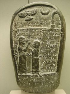 an ancient object with writing on it and two people sitting at the table in front of it