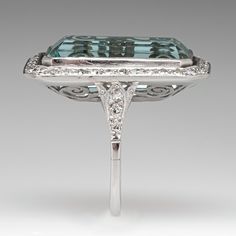 This mazing vintage cocktail ring is centered with one (1), bezel set, emerald cut natural aquamarine that is bordered with thirty-six (36), bead set, round single cut diamonds. The shoulders of the ring are each accented with three (3), bead set, round single cut diamonds. The gemstones are bordered with milgrain edging. The ring measures 28.9mm X 18.7mm at the top, rises 9.1mm above the finger, tapering to 1.7mm wide and 1.3mm thick at the base of the shank. It is currently a size 7. Art Deco Diamond Emerald Ring Octagon Shape, Formal Emerald Ring With Rectangular Stone And Bezel Setting, Elegant Emerald Cut Topaz Ring With 17 Jewels, Elegant Emerald Cut Topaz Ring, Formal Emerald Ring With Diamond And Rectangular Stone, Luxury Aquamarine Octagon Ring, Luxury Rectangular Topaz Anniversary Ring, Formal Emerald Ring With Rectangular Diamond, Art Deco Rectangular Ring With Accent Stones