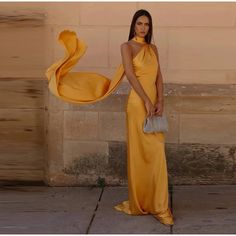 a woman in a yellow dress is standing on the sidewalk with her hand over her shoulder