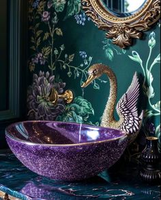 a purple bowl sink sitting on top of a marble counter next to a wall mounted mirror