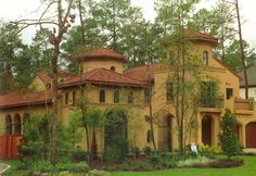 a large yellow house surrounded by trees and bushes