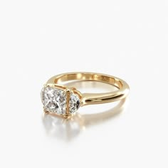 a yellow gold ring with two princess cut diamonds