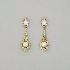 two pairs of earrings with pearls and diamonds in them on a gray surface, one is gold