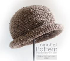 a crocheted brown hat on a metal stand with the word pattern above it