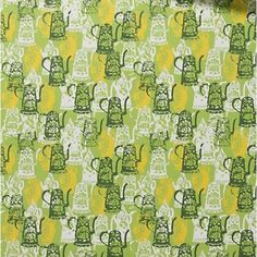 a green and yellow wallpaper with teapots printed on the back, next to a potted plant