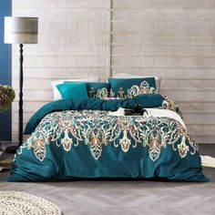 the bed is covered with teal colored comforters and pillows, along with a white rug