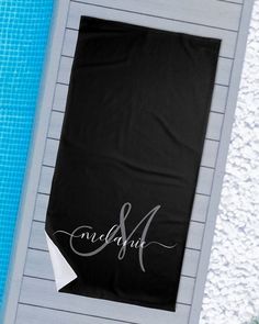 a towel that is sitting on top of a table next to a swimming pool with the word love and marriage written on it