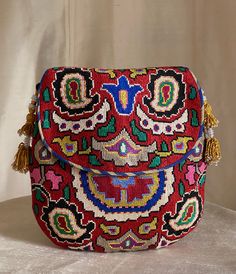 "Medium size Flat Silk Petit Point Handbag created and handmade in Uzbekistan. Lined with silk and cotton ikat fabric, hand woven silk straps and tassels and a magnetic snap closure. Each handbag is hand drawn onto cotton canvas, inspired by original designs from Uzbekistan textile history.  8.5\" high x 8.5\" width, top opening 6\" wide approx. 64\" strap x 1/2\" width.  Can fit largest sizes of iPhone and Android. 100% silk petit point with handwoven silk and cotton ikat lining. The strap is b Artisan Multicolor Embroidered Bag For Festivals, Artisan Bag With Multicolor Embroidery For Festivals, Artisan Multicolor Embroidery Bag For Festivals, Traditional Multicolor Pouch Shoulder Bag, Artisan Bags With Multicolor Embroidery For Festivals, Handmade Multicolor Tapestry Shoulder Bag, Multicolor Folk Bags For Festivals, Traditional Woven Shoulder Bag, Artisan Red Embroidered Bag