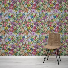 a chair sitting in front of a colorful wallpaper with flowers on the walls and floor