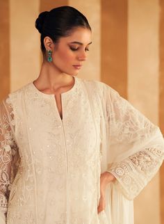 Step into refined elegance with the ivory new embroidered kurta, perfectly paired with luxurious silk pants and a delicate net embroidered dupatta. The kurta features intricate embroidery in soft ivory, adding a touch of sophistication. The silk pants offer a sleek, complementary finish, while the net dupatta, adorned with delicate embroidery, completes the ensemble with an ethereal charm. Ideal for both festive and formal occasions, this outfit effortlessly blends classic grace with contemporar Semi-stitched White Unstitched Suit With Naqshi, Festive White Salwar Kameez With Naqshi, Designer White Salwar Kameez With Naqshi, Designer White Naqshi Salwar Kameez, Designer White Salwar Kameez With Naqshi Detailing, Elegant White Anarkali Set With Naqshi Detail, Bollywood Style White Naqshi Salwar Kameez, White Naqshi Sharara For Reception, White Anarkali Kurta With Naqshi