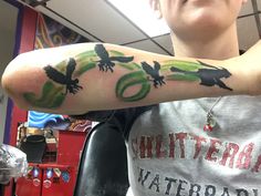 a person with a green and black tattoo on their arm in a room full of other things