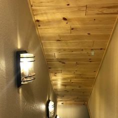 the hallway is lined with wood planks and has two lights on either side of the wall