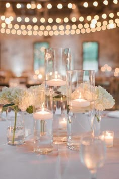 the centerpieces are filled with white flowers and lit candles for an elegant touch