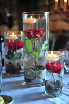 there is a vase with roses in it and rocks on the table next to it