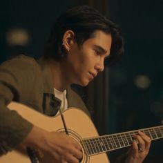 a young man is playing an acoustic guitar