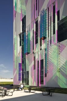 people sitting on benches in front of a multicolored building