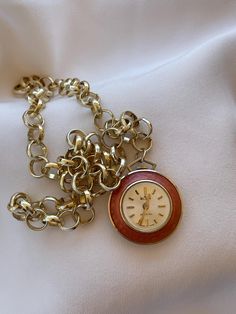 Elegant 1960's Vintage Art Deco Swiss women's Pendant Watch Wilson golden color case inlaid with apricot color enamel with clear white color dial. Very elegant classic present for women for every occasion. Collectible Swiss pendant ladies watch with new stainless steel necklace in golden color. An accent that would make every woman look stunning. Amazing present for vintage watch lovers. Very elegant classical gift for ladies. Pre-owned. The item has been used previously. It may have some signs of cosmetic wear but is fully operational and functions as intended. Checked and serviced. Exceptional gift for the loved one. The watch is in excellent condition and has no visible defects (please, see the pictures). Watch runs properly when tested. Should be wound up regularly on every 24 hours. T Retro Round Watch As Gift, Retro Round Watch For Gift, Vintage Pocket Watch Gift, Retro Gold-tone Jewelry For Gift, Retro Gold-tone Jewelry Gift, Vintage Round Chain Jewelry, Vintage Gold Round Watches, Gold Watches Suitable For Gifts, Retro Gold Round Pendant Jewelry