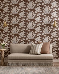 a couch and table in front of a wallpapered room with flowers on it