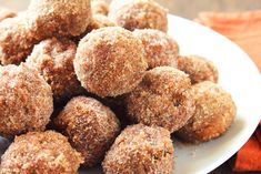 a white plate filled with sugared donuts sitting on top of a wooden table