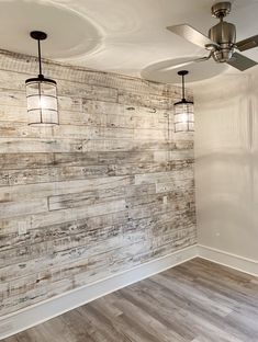 an empty room with wood paneling on the wall and ceiling fan hanging from the ceiling